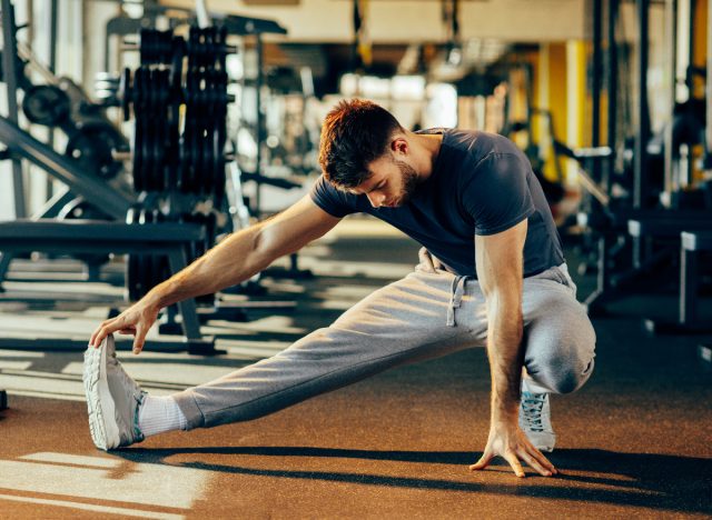 man warming up, stretching at the gym