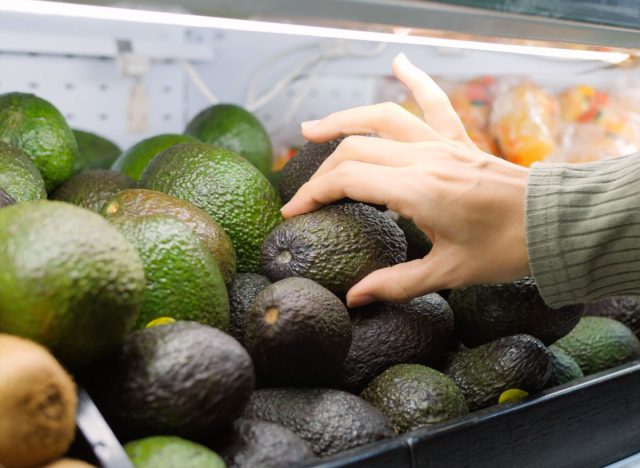 woman choosing avocado at the grocery store
