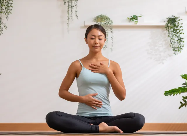 woman doing deep breathing exercises on yoga mat