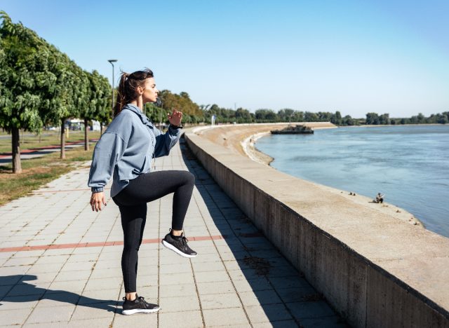 woman doing high knees standing cardio workout by the water