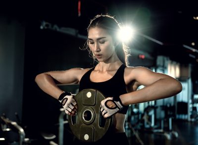fitness woman holding a weight plate at the gym, concept of exercises to build a better body