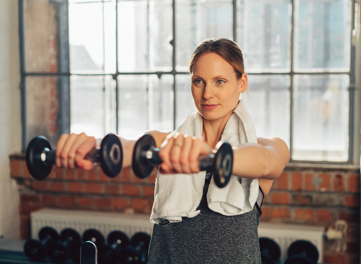 fit woman holding free weights, demonstrating dumbbell exercises to change your body shape after 40