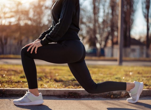 close-up woman doing lunges during outdoor walk to burn more belly fat