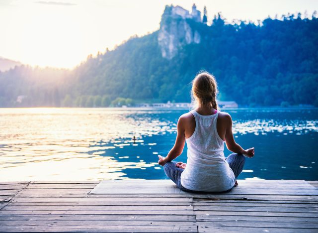 woman meditates by the lake