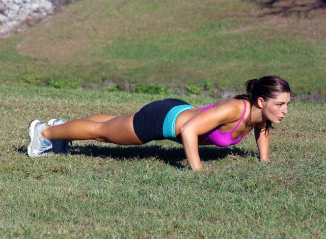 fit woman doing outdoor pushups on the grass