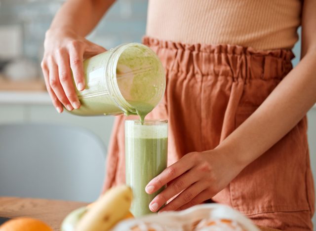 woman pouring green smoothie into a glass