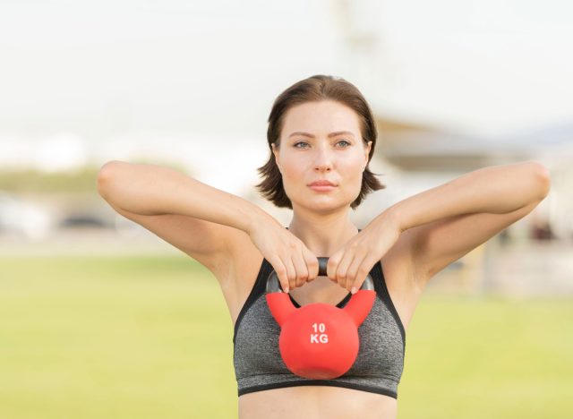 woman demonstrating upright row exercises with kettlebell to lose shoulder fat