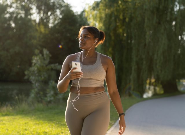 woman listening to music while doing walking workout in park