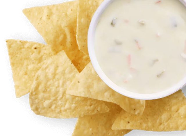 cup of Chipotle queso and chips on a white background