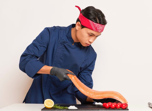 Chef carefully puts salmon filet on the table 