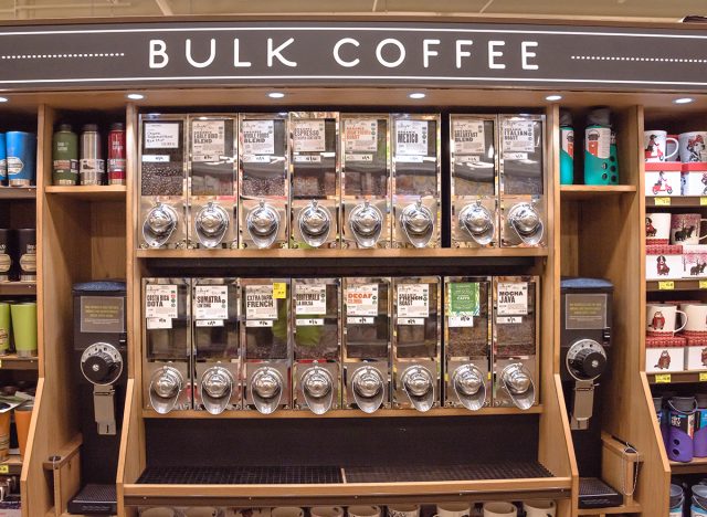 Row of variety organic raw coffee beans in vending machine at Whole Foods store.