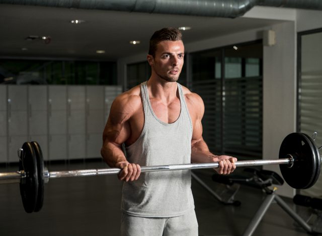 muscular man doing barbell bicep curls, concept of exercises for men to bulk up