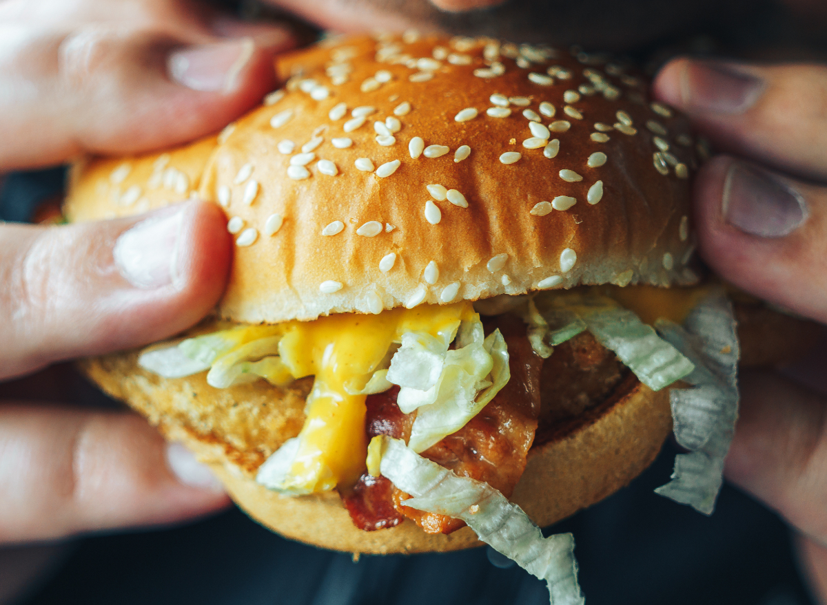 close-up of man eating cheeseburger, concept of testosterone-killing foods