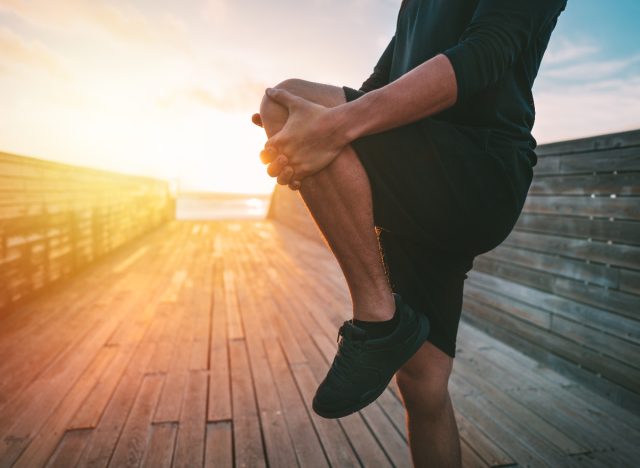 close-up man stretching on boardwalk after workout