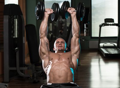 muscular fitness man doing dumbbell bench press on bench, concept of exercises to build muscle mass