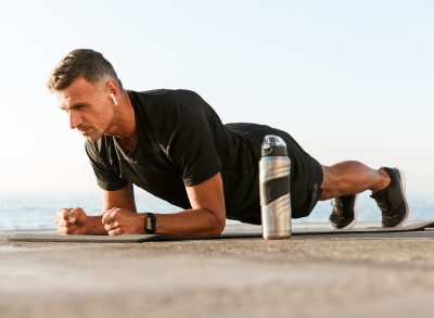 fit man doing forearm plank outdoors, concept of the best exercises for men to build strength without equipment