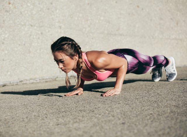 fit woman at the bottom of a pushup, concept of exercises to lose belly fat and build muscle