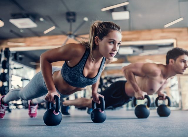 fitness couple doing kettlebell pushups fat-burning exercises to lose weight at the gym