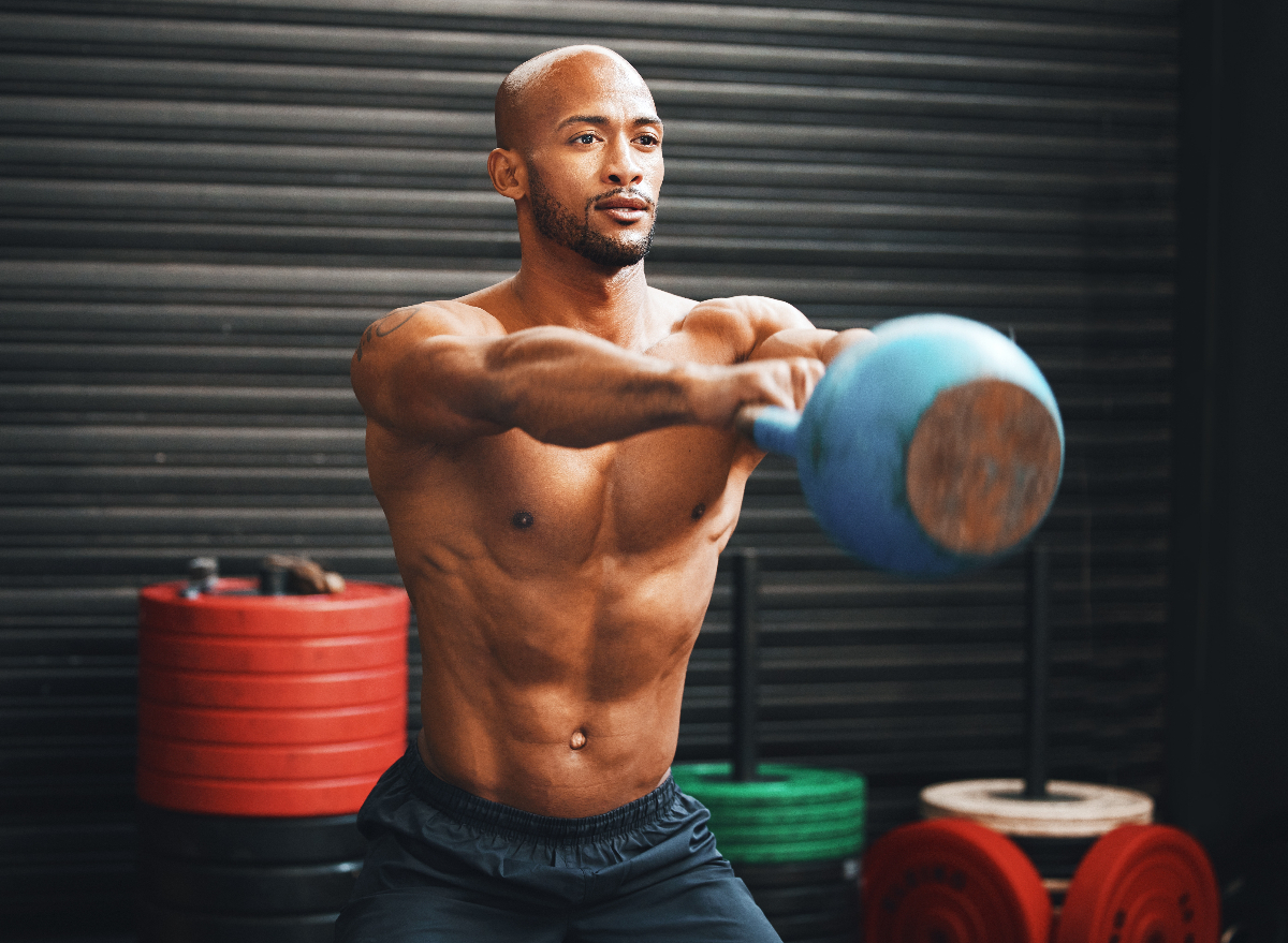 Concentrated man doing dumbbell workout. Well trained body with bulky  muscles. Sport equipment and weightlifting. Stock Photo