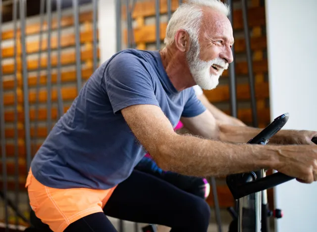 happy senior man doing indoor cycling endurance exercises at the gym