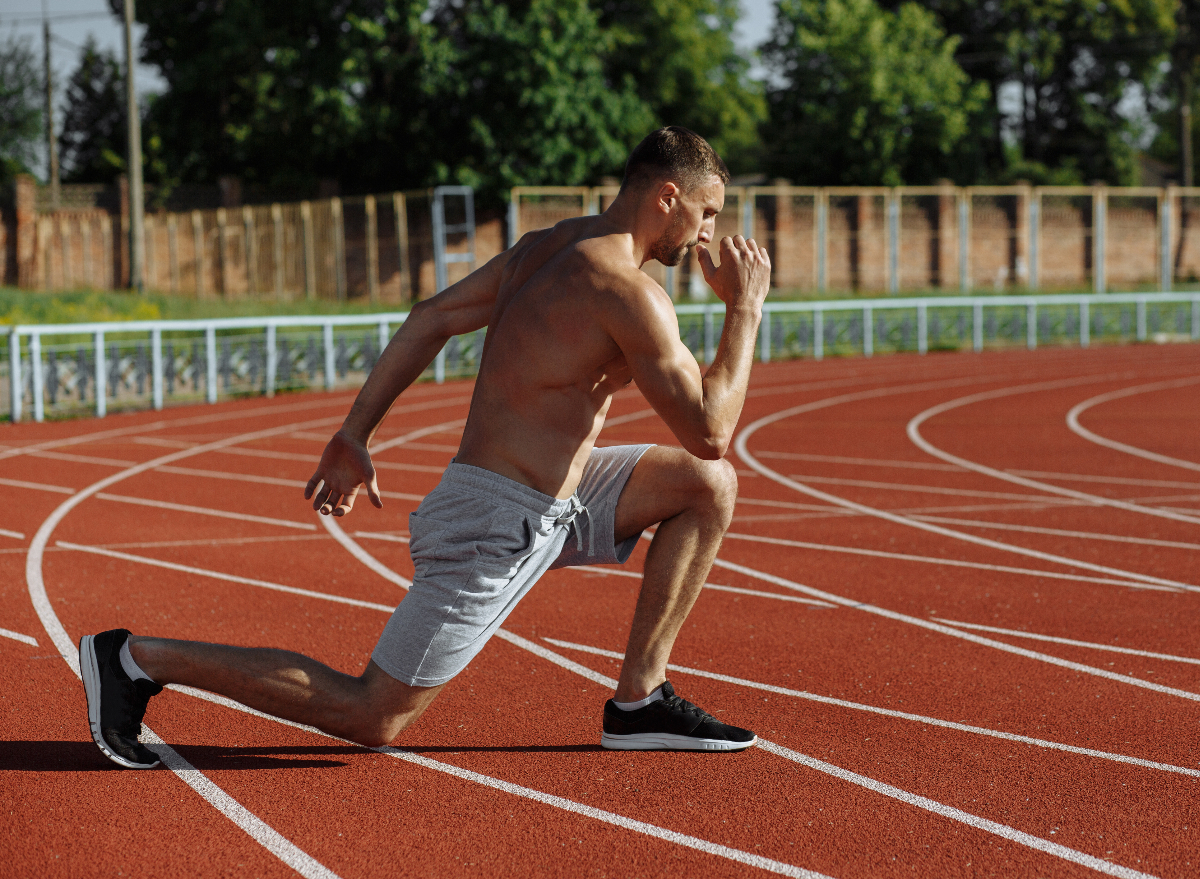 fit muscular man doing reverse lunges on track