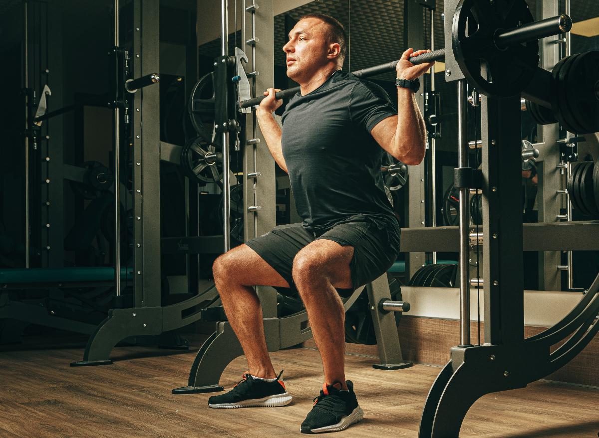 man doing smith machine squats, concept of machine exercises for men to build powerful legs