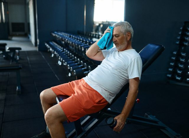 older man tired sitting on workout bench during workout