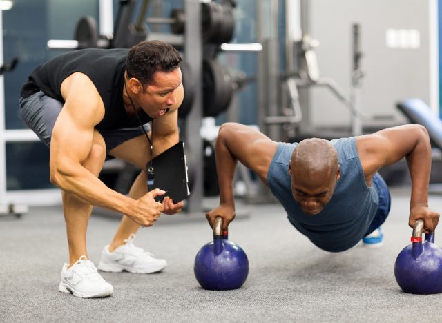 man doing pushups, working with personal trainer, concept of tips for men to lose belly fat