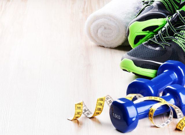 man's sneakers, dumbbells, towel weight loss fitness concept