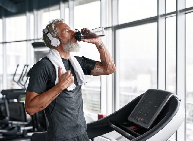man drinking water, hydrating at the gym
