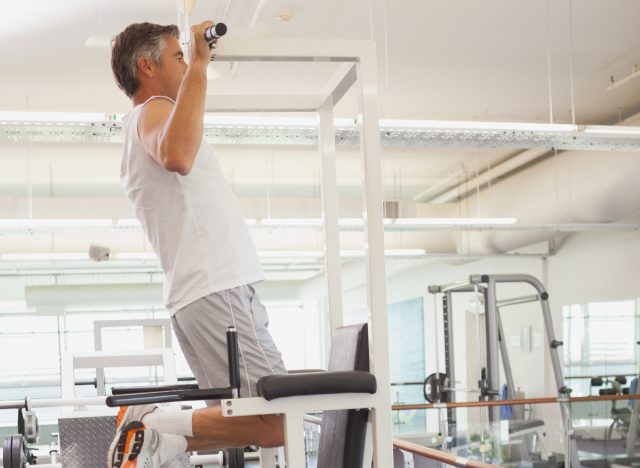 mature man doing pull-ups at the gym