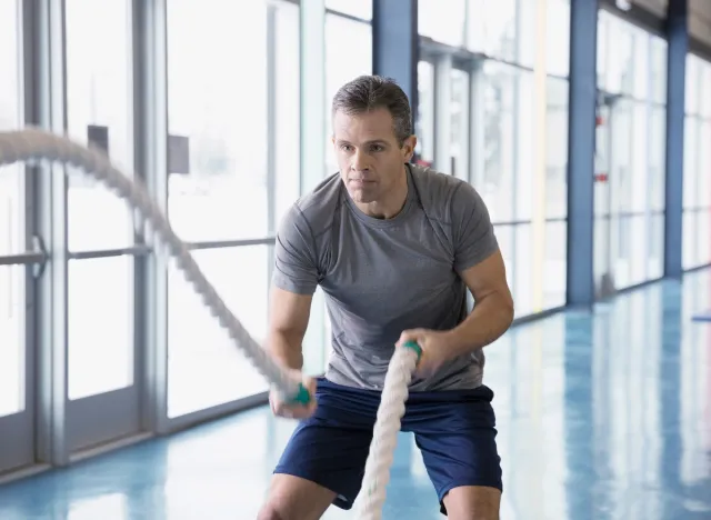 middle-aged man doing battle ropes endurance exercises to improve stamina