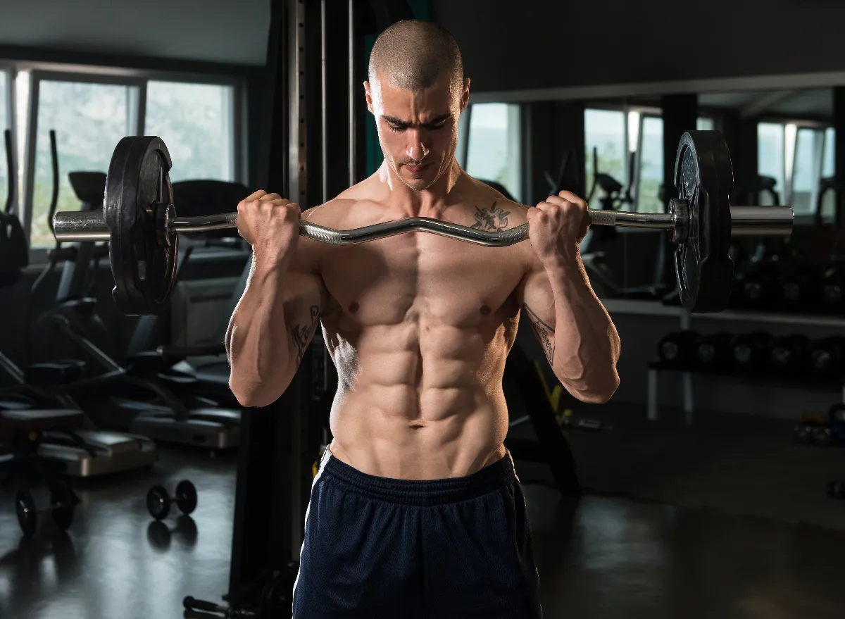 muscular man doing barbell bicep curls at the gym, concept of strength exercises for men to bulk up fast