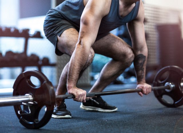 muscular man lifting barbell at the gym, close-up