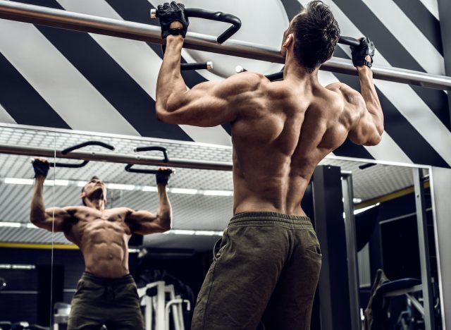 muscular man at the gym doing pull-ups, concept of workouts for men to build muscle mass