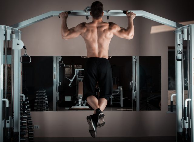 muscular man doing pull-ups at the gym, doing a workout for men to build muscle