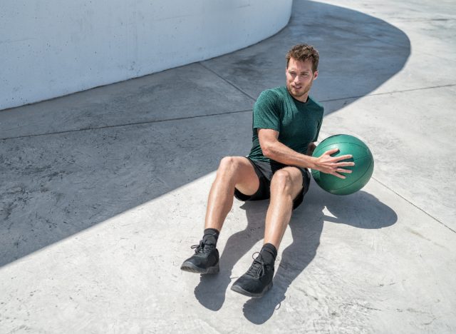 man doing Russian twist exercise with medicine ball