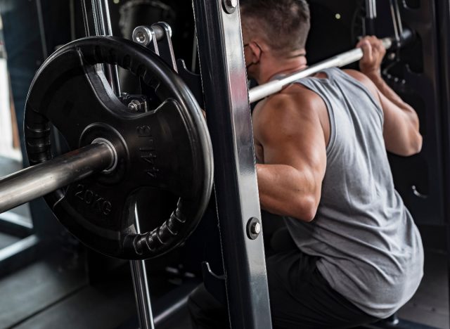 close-up of man doing squats on Smith machine, concept of machine exercises for men to build powerful legs