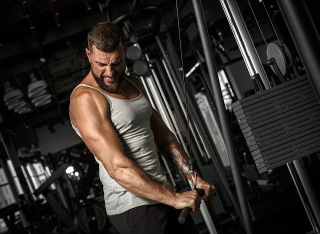 muscular man doing straight arm cable pulldowns, part of workout for V-taper back