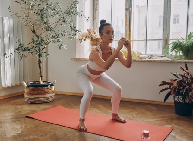 woman doing bodyweight squats on yoga mat