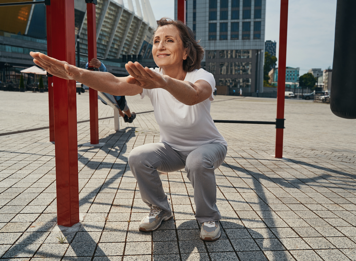 mature woman doing bodyweight squats exercise, concept of daily workout for lower-body strength as you age
