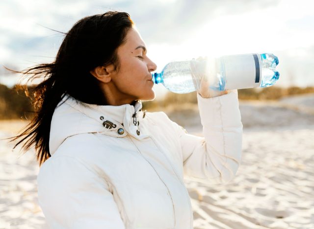 woman drinking water bottle outside