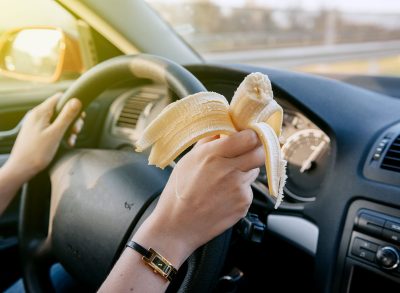 woman eating a banana while driving in a car