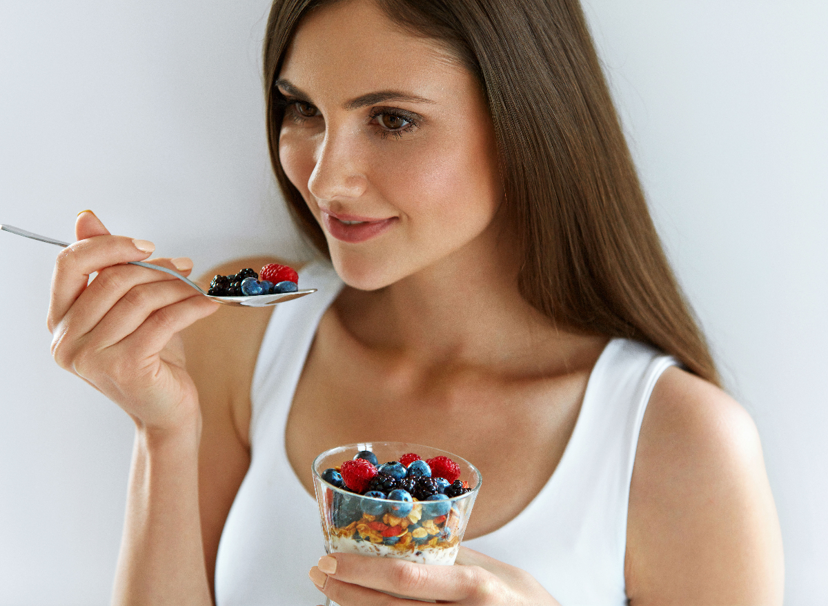 woman eating fresh berries, parfait, concept of how to lose 10 pounds quickly