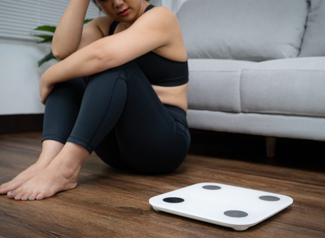 woman sitting next to scale frustrated with weight loss