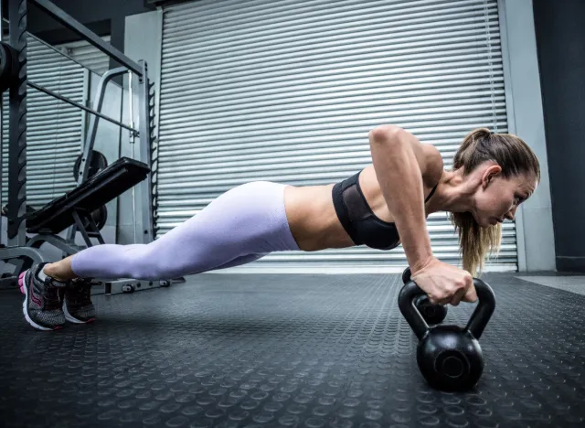 woman doing kettlebell pushups at the gym, concept of fat-burning exercises to lose weight