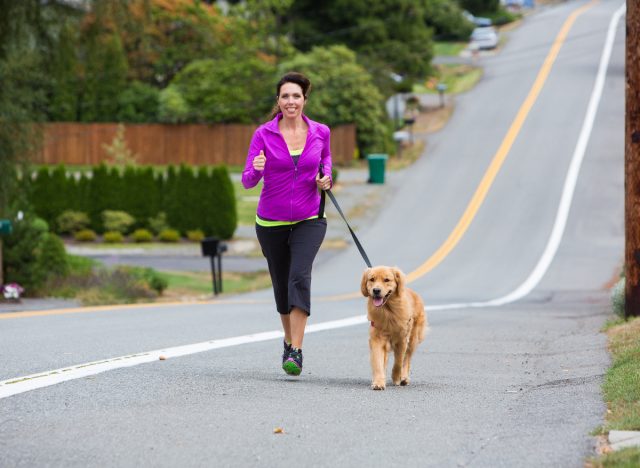 fit woman running uphill with her dog
