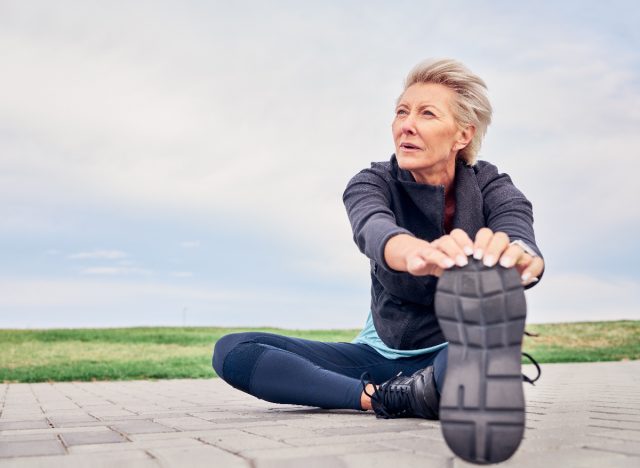 mature woman stretching, cooling down after run