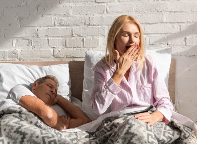 unavená zralá žena zívající v posteli, koncept návyků, které ničí pokrok v hubnutí