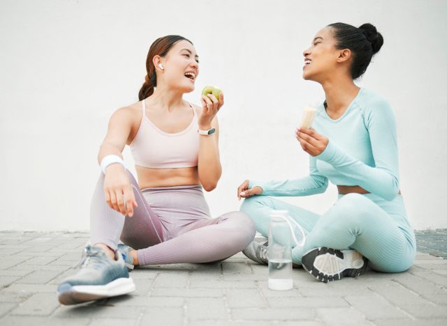 two fitness women eating fruit after workout